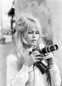 Photographie en noir et blanc de Brigitte Bardot tenant un appareil de photographie